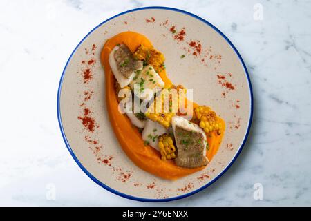 Delizioso pesce sogliola con crema di carote e mais. Tavolo con vista dall'alto e decorazioni. Foto Stock