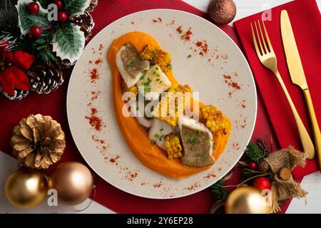 Delizioso pesce sogliola con crema di carote e mais. Tavolo con vista dall'alto e decorazioni natalizie. Foto Stock