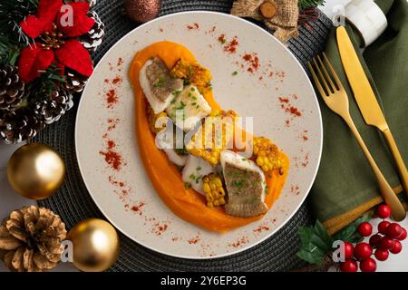 Delizioso pesce sogliola con crema di carote e mais. Tavolo con vista dall'alto e decorazioni natalizie. Foto Stock