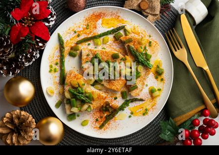 Pesce spada alla griglia con asparagi verdi. Tavolo con vista dall'alto e decorazioni natalizie. Foto Stock