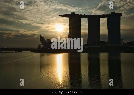 Singapore, 2 dicembre 2023: Vista dell'hotel Marina Bay Sands e del museo delle scienze artistiche a Marina Bay all'alba, in silhouette contro il sole dell'ora d'oro. Foto Stock