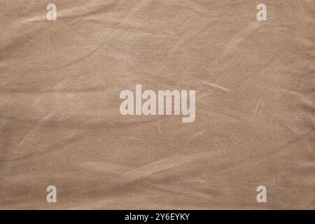 Vista ravvicinata di un tessuto marrone rugoso che mostra le sue fibre naturali e dettagli irregolari della superficie in un'illuminazione soffusa Foto Stock