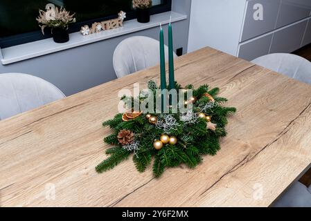 Una decorazione natalizia fatta di rami di conifere e un pezzo di legno, steso sul tavolo nella sala da pranzo. Foto Stock