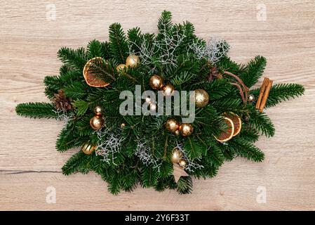 Una decorazione natalizia fatta di rami di conifere e un pezzo di legno, steso sul tavolo nella sala da pranzo. Foto Stock