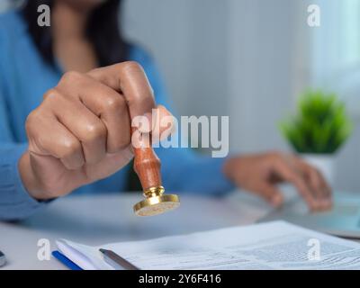 La donna d'affari timbra a mano con timbro approvato sul testo documento approvato alla scrivania, convalida e gestisce documenti e accordi aziendali, approvazioni Foto Stock