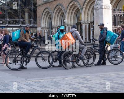 Basta mangiare e consegnare il cibo i corrieri e-bike si riuniscono alla stazione di Liverpool Street, prima dell'ora di pranzo Foto Stock