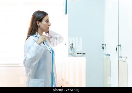 Giovane medico donna in uno spogliatoio che mette i suoi vestiti nell'armadietto Foto Stock