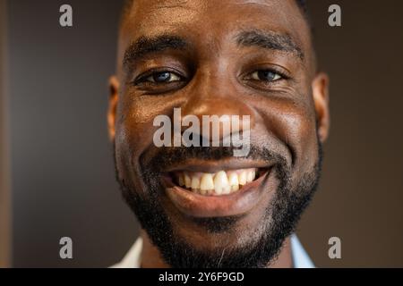 Sorridente afroamericano con la barba che guarda direttamente alla macchina fotografica, mostrando felicità e fiducia Foto Stock