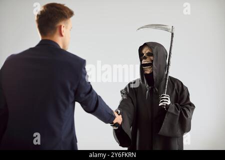 Triste Mietitore della morte con la spalla falce che incontra nuova vittima, giovane nella paura della morte, morente Foto Stock