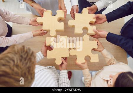 Primo piano del team aziendale che collega i rompicapo in legno in Office Foto Stock