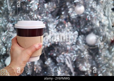Tazza di caffè da asporto con sfocato albero di Natale sullo sfondo Foto Stock