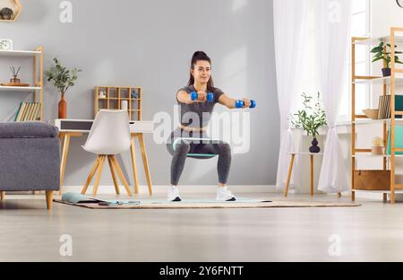 Donna che esegue squat e si allunga con Resistance Band a casa Foto Stock