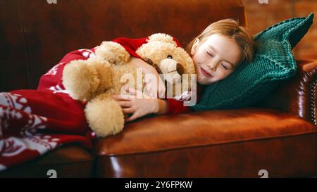 Piccola ragazza dorme vicino ad albero illuminato sognare di miracoli di natale Foto Stock