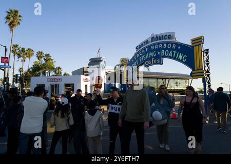 La folla si riunisce sotto il cartello del porto degli yacht di Santa Monica, godendosi una giornata di ristoranti all'aperto, pesca sportiva e nautica lungo il pittoresco lungomare. Foto Stock