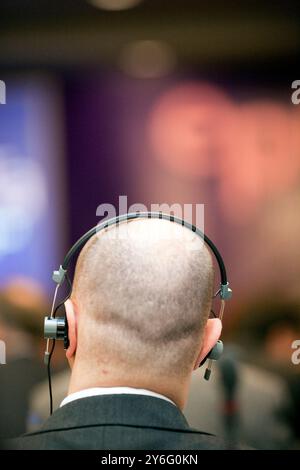 Un uomo partecipa attivamente a una conferenza a Dublino, utilizzando le cuffie per i servizi di traduzione. Foto Stock