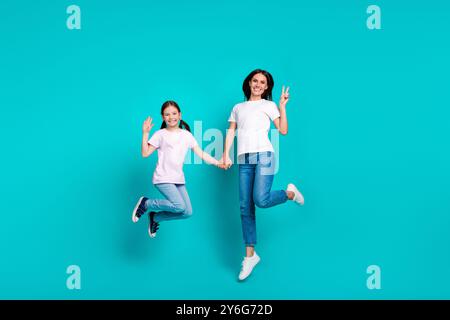 Foto di ragazze di famiglia pazze e allegre indossano abiti eleganti che saltano a mano il segno a V isolato su sfondo di colore ciano Foto Stock