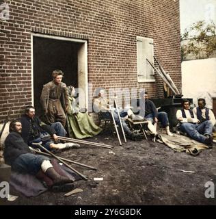 Creato da James Gardner. La fotografia mostra i soldati all'esterno di un edificio ospedaliero in mattoni a Fredericksburg, Virginia, che si stanno riprendendo dalle ferite ricevute durante le battaglie della "campagna Wilderness". La donna seduta sulla porta e' l'infermiera volontaria Abby Hopper Gibbons di New York. (Fonte: Discendente Angela Schear, ottobre 2013). Testo Orinial dalla scheda che accompagna l'immagine: Hospital at Fredericksburg, Virginia., maggio, 1864. Questo è uno degli ospedali istituiti dalla Sanitary Commission, a Fredericksburg, Virginia, durante la campagna Wilderness nel 1864. I feriti vengono dal Kearney' Foto Stock