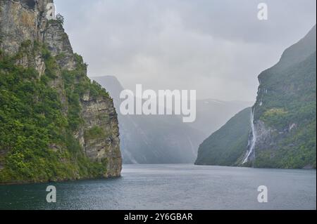 Fiordo di Geiranger con cascata circondata da rocce e montagne con cielo coperto, Geiranger, Geiranger, Geiranger, Stranda, Romsdal, Norvegia, Europa Foto Stock