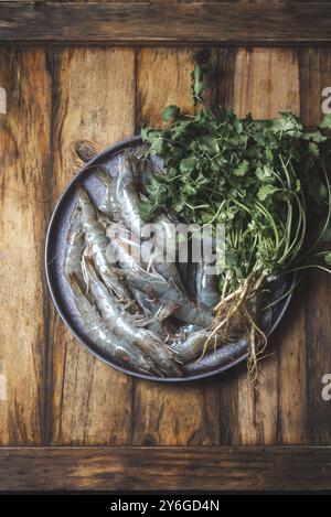 Cibo, cibo, pesce crudo. Gamberi freschi con piatto grigio coriandolo. Fondo in legno Foto Stock