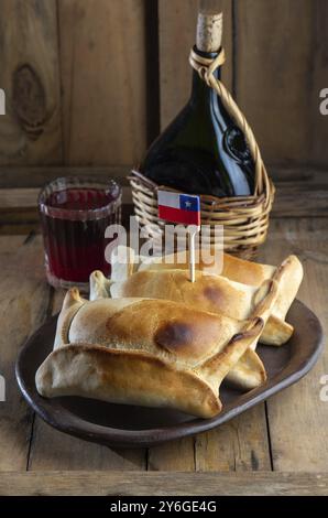 Cibo, concetto del giorno dell'indipendenza cilena. fiestas patrias. Tipico empanadas de pino al forno, vino o chicha, cappello e giochi. Piatto e bevande su 18 S. Foto Stock