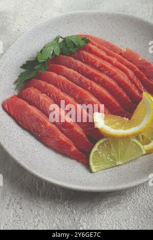 Cibo, salmone salmone, affumicato freddo, tagliato a fette, su un piatto grigio, con limone e prezzemolo, vista dall'alto, primo piano, nessuno Foto Stock