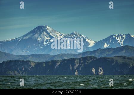 Splendido paesaggio estivo di Kamchatka, tre rocce dei Fratelli nella Baia di Avacha e cono del Vulcano. Estremo Oriente russo Foto Stock