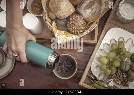 Colpo di testa di un tavolo da colazione in legno con pane, frutta e caffè. Colori marroni attenuati Foto Stock