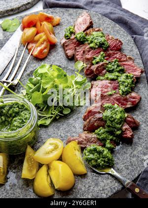 Cibo, fette di bistecca di manzo con salsa chimmichuri su piatto di pietra grigio Foto Stock