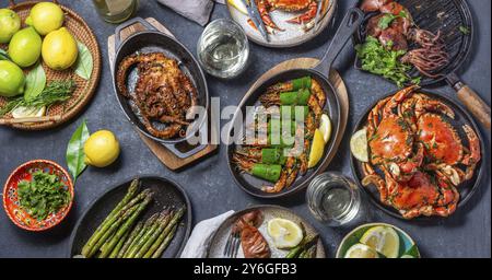 Cibo, cibo, tavolo fisso con piatti a base di pesce, granchi cotti, gamberi tigre, polpo alla griglia e calamari su piatti e padelle grigliate in ghisa, vino bianco. T Foto Stock