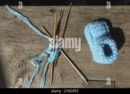 Maglieria di calze di lana blu, aghi per maglieria su un tavolo di legno Foto Stock