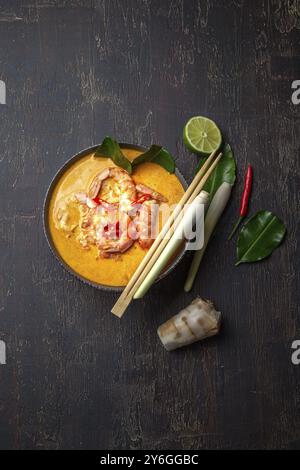 Cibo, cibo, gamberetti Tom Yam Kung in una ciotola grigia con spezie thailandesi su un autentico vassoio con vista dall'alto, sfondo in legno Foto Stock