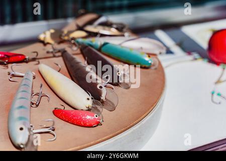 Le colorate lure da pesca con ganci sono disposte su un tavolo, attrezzi per i pescatori nella pesca d'acqua dolce e d'acqua salata Foto Stock