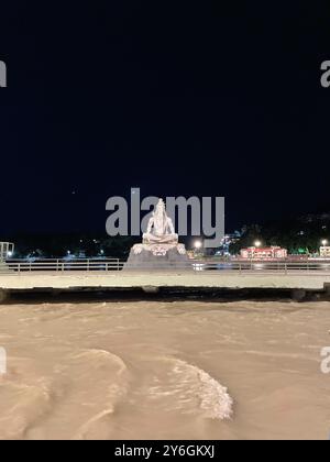 Una vista notturna di una statua di Lord Shiva sulle rive del fiume Gange a Rishikesh, India. Foto Stock