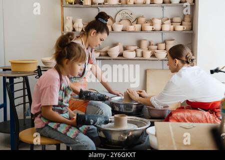 Bambini e adulti che creano ceramiche insieme in un luminoso studio Foto Stock