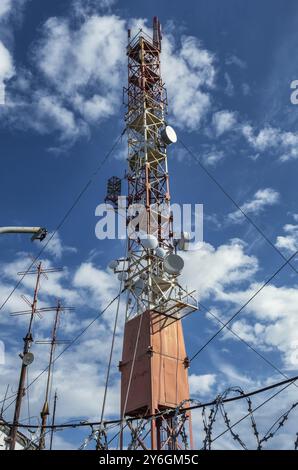Le comunicazioni radio si innalzano contro il cielo blu con le nuvole Foto Stock