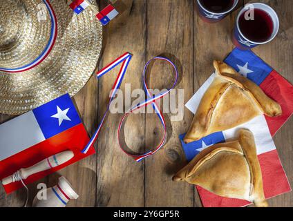 Fotografia gastronomica, concetto di giornata dell'indipendenza cilena. fiestas patrias. Empanadas, vino o chicha al forno tipici, imboque grasse e giocosa. Decorazione per 18 persone Foto Stock