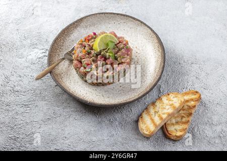 Cibo, cibo, TARTARE DI pesce tonno su piatto grigio Foto Stock