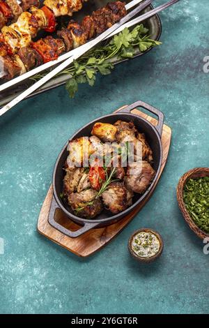 Cibo, cibo, carne grigliata alla griglia, maiale, pollo e verdure su una teglia in ghisa. Spiedini grigliati su sfondo giallo in legno. Vista dall'alto Foto Stock