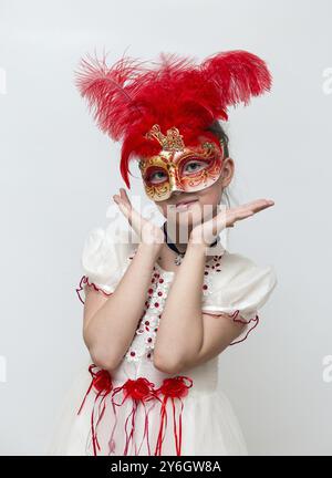 Adorabile bambina con maschera di carnevale veneziana su sfondo bianco Foto Stock