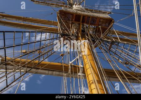 Vista ad angolo basso dei montanti in legno della barca a vela e delle attrezzature sotto il cielo blu con nuvole Foto Stock