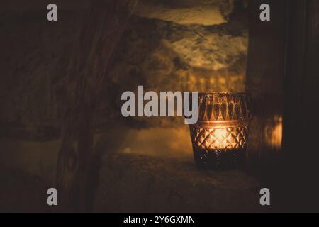 Un bicchierino di candela a lume di tè sulla parete di roccia con struttura in legno. Decorazioni per interni Foto Stock