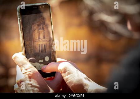 Turista che scatta una foto con uno smartphone o un telefono cellulare del Tesoro dal punto di vista di Petra, vicino a Wadi Musa, Giordania, Asia Foto Stock