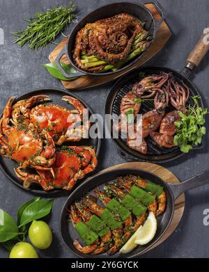 Cibo, tavolo fisso con piatti a base di pesce, granchi cotti, gamberi tigre, polpo alla griglia e calamari su una teglia di ghisa Foto Stock