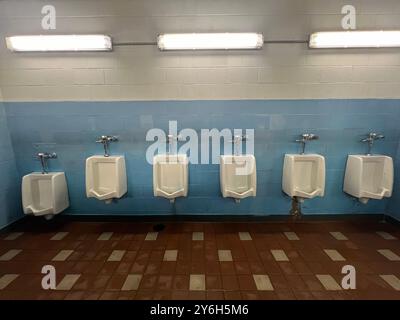 Bagno degli uomini pulito con orinatoi allineati su un muro in un bagno pubblico a New York. Foto Stock