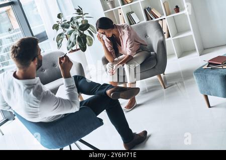 Sta attraversando un periodo difficile. Giovane donna frustrata che risolve i suoi problemi mentali mentre siede alla sessione di terapia con la psicologa Foto Stock