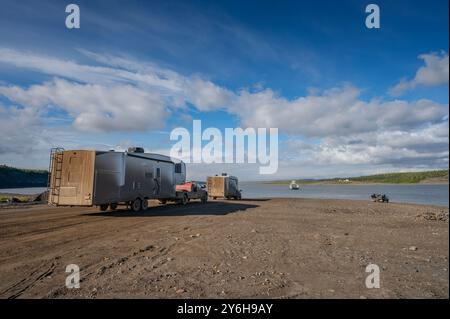 I camper coperti di fango aspettano l'attraversamento del fiume Mackenzie sulla Dempster Highway Foto Stock