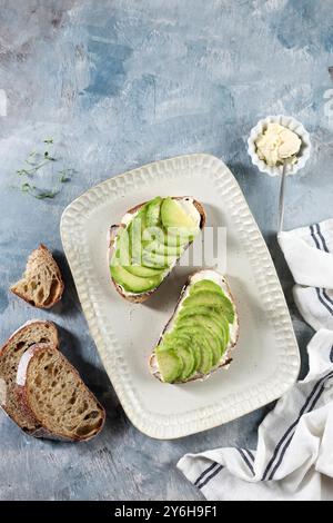 Pane a pasta rigna aperto con vista dall'alto con avocado a fette, crema di formaggio e miele Foto Stock