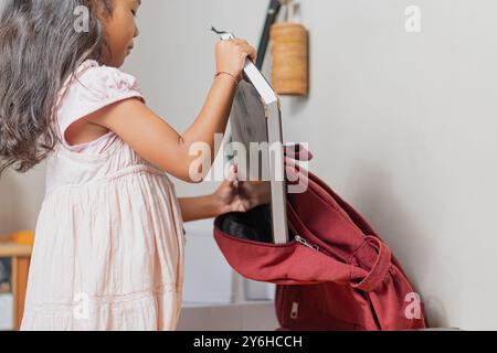 Una ragazza ha in mano un libro. Il libro è rosso e ha una cerniera. La ragazza sta indossando un vestito rosa Foto Stock