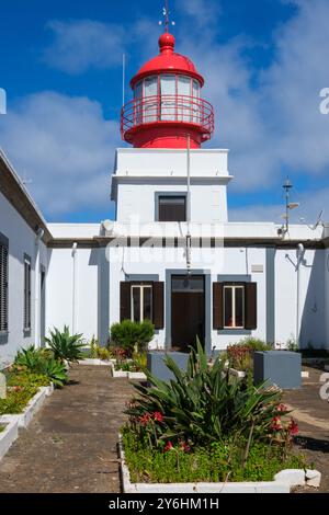 Recinto di luce rossa luminosa sopra l'edificio del faro dipinto di bianco a Ponta do Pargo, la punta occidentale di Madeira. Foto Stock