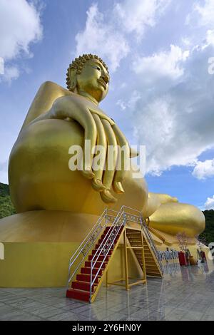 La statua dorata del grande Buddha a Wat Khao Wong Phrachan, con gradini per i visitatori che accedono alla mano destra dell'immagine, Lopburi Foto Stock